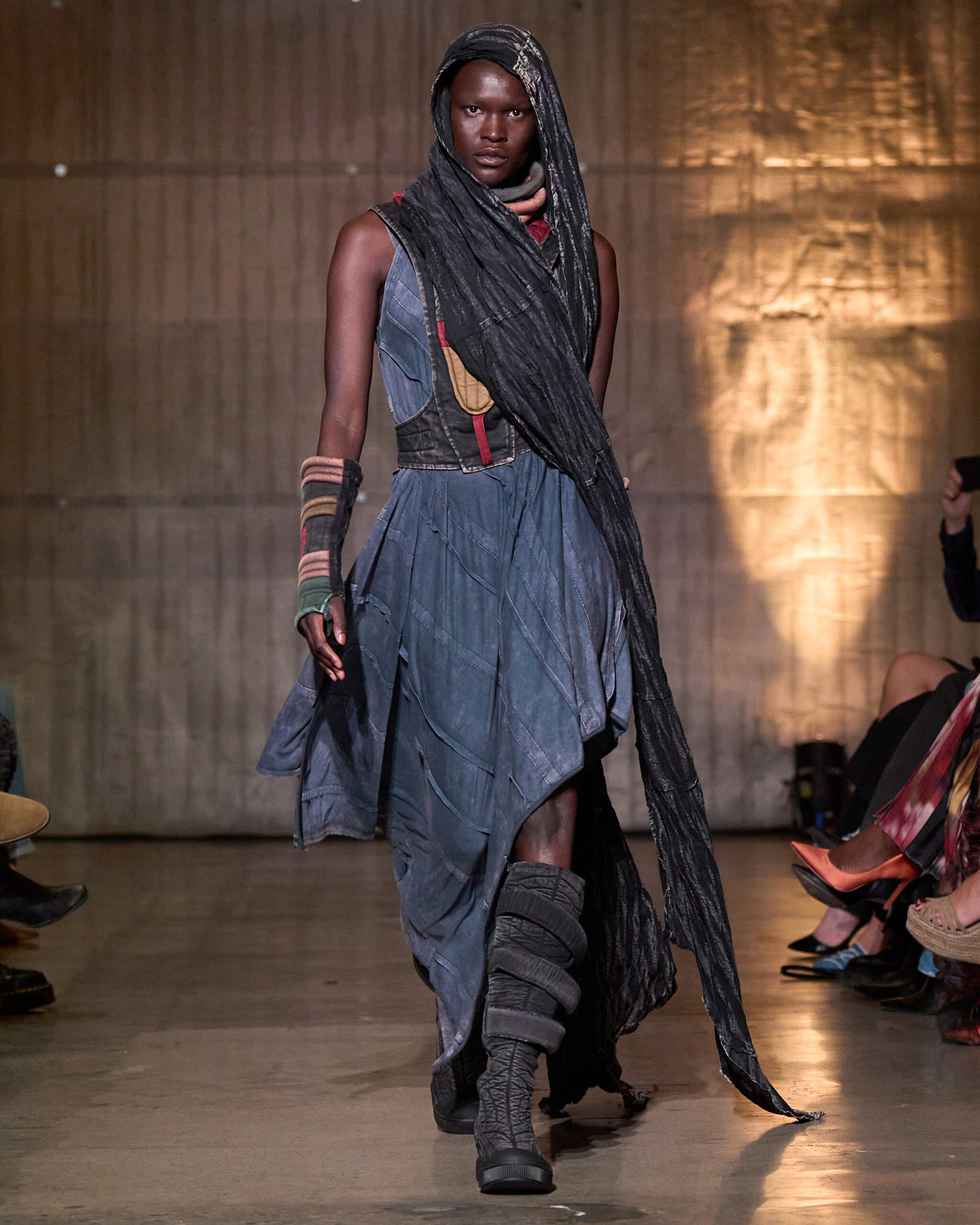 Model wearing a layered hooded outfit on the Demobaza runway